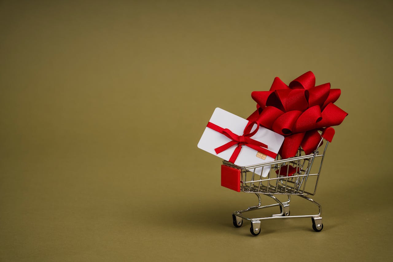 A Mini Shopping Cart with a Bank Card Wrapped in a Red Ribbon 